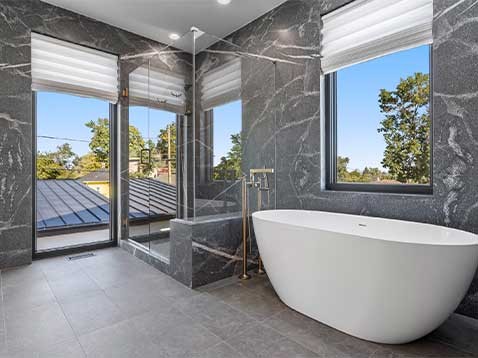 A grey stone modern bathroom with big open windows